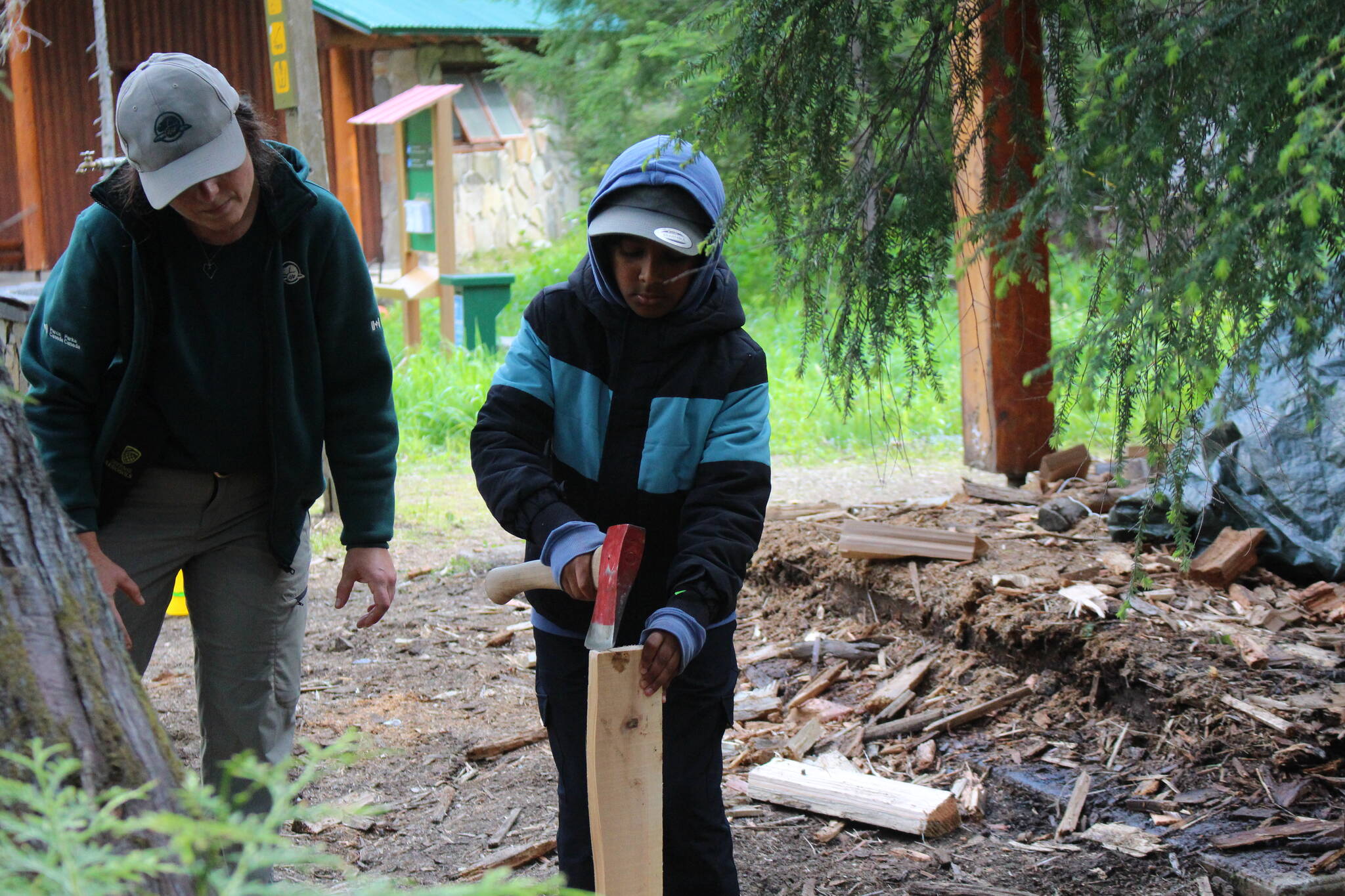 A new camper is taught by Goldie Rich how to split wood and make kindling. (Zachary Delaney/Revelstoke Review)