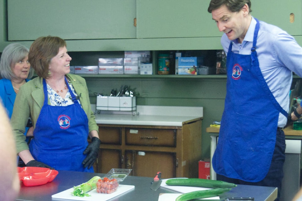 North Island MLA Michele Babchuk ties the apron up on Social Development and Poverty Reduction Minister Sheila Malcolmson as B.C. Premier David Eby adjusts his during the announcement of $7.5 million to the United Way by the province for Food Hubs. Photo by Edward Hitchins/Campbell River Mirror