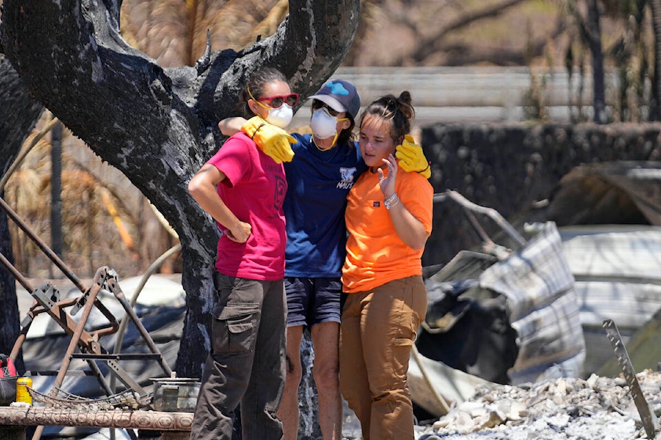 Women hug after digging through rubble of a home destroyed by a wildfire on Friday, Aug. 11, 2023, in Lahaina, Hawaii. (AP Photo/Rick Bowmer)