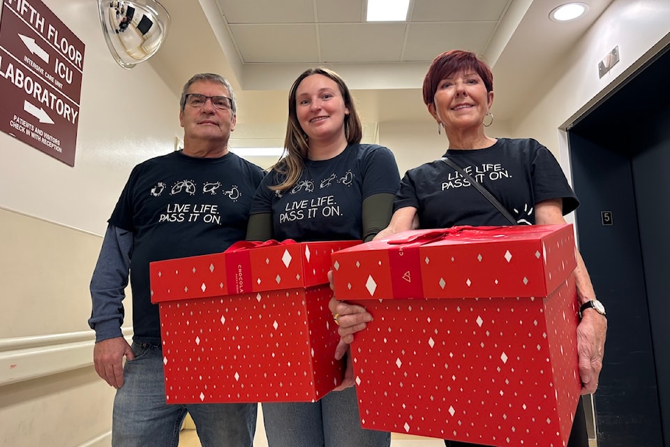 From left to right: Steve Farmer, Kelsey Farmer and Faye White posing with boxes of caramel popcorn.