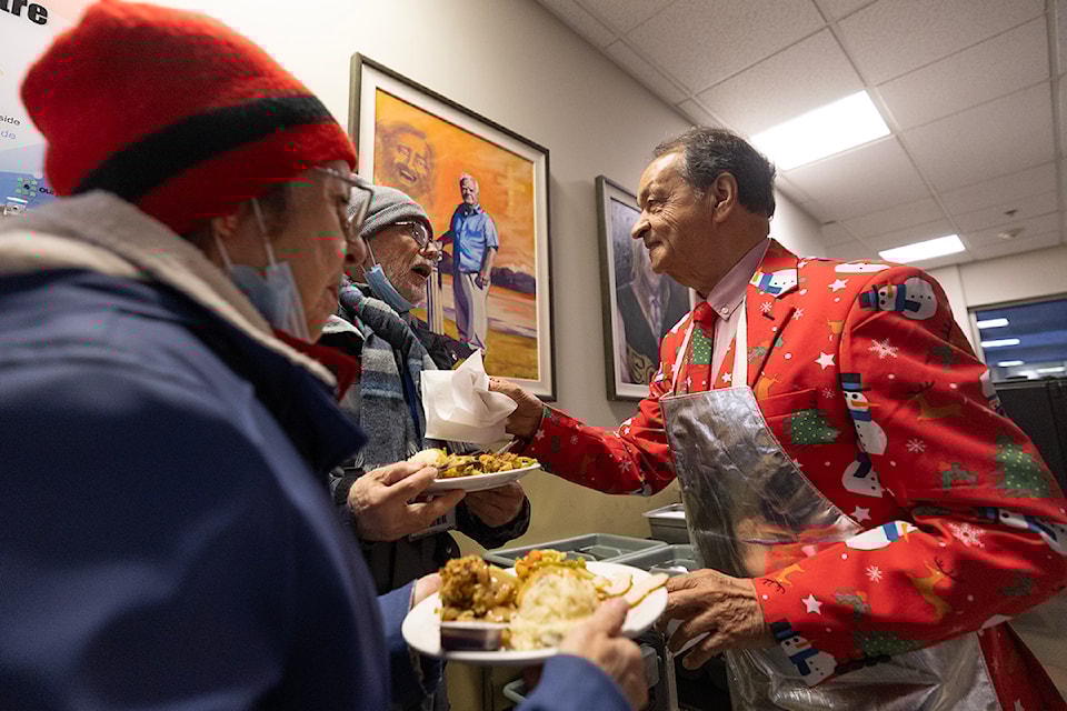 Gordy Dodd (right) gives utensils to Luis Ochoa (center) and Maggie Parsons (left) at Gordy Dodd’s 26th Annual Our Place Christmas Dinner at the Our Place Society in Victoria.