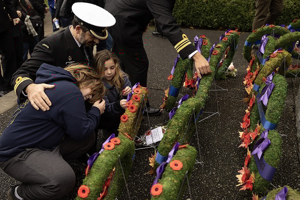 A young child pins a poppy to a wreath at the Cenotaph at Esquimalt Memorial Park at the Remembrance Day ceremony at the Esquimalt Memorial Park in Esquimalt. (Arnold Lim / Black Press Media.)