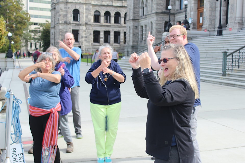 Lisa Anderson, president of the Greater Vancouver Association of the Deaf, leads the crowd in a joyous signing of 'Happy International Day of Sign Languages'.