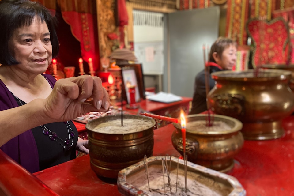 Nora Butz, president of the Yen Wo Society, lights incense in the Tam Kung Temple in Victoria.