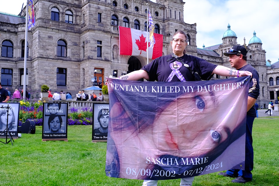 Tanya McMahon poses with a banner showcasing her daughter who passed away from a toxic drug overdose. 
