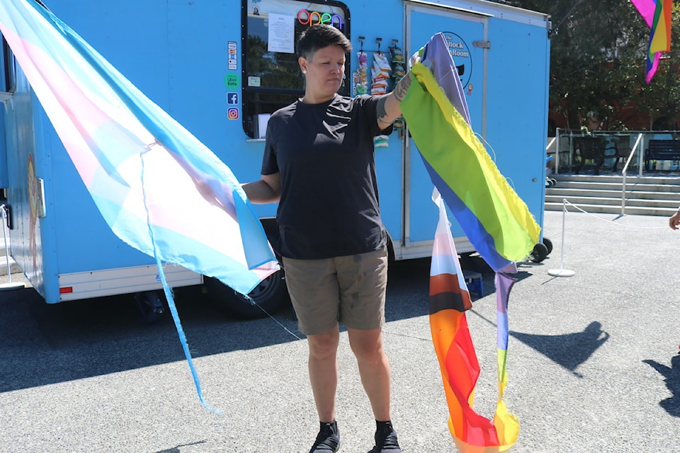 Owner of the Bannock Room Mandy Large holds a transgender flag and Pride flag, both vandalized.