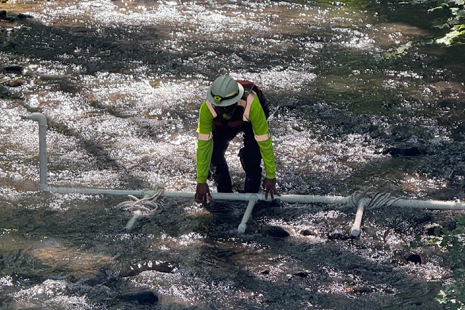 A responder positions a sparging unit in Indian Creek. This technique is used to agitate and release fuel trapped under debris or rocks so it can be collected with absorbent materials.