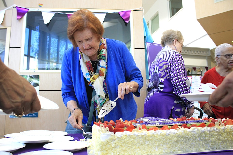 A Royal Jubilee Hospital Auxiliary volunteer cuts cake to celebrate the charity's 101st birthday.