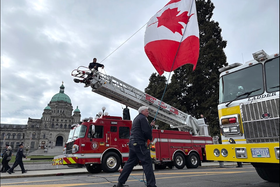 In preparation for the fallen firefighters memorial parade, members of the Victoria and Oak Bay fire departments hoist the Canadian flag over Belleville Street in Victoria.