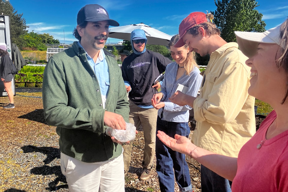 Raj Behari hands out small scoops of 'magic beans' that Shellter Rapid Compost made of Victoria-area coffee waste and shells. 