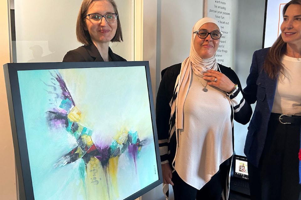 MC Lauren Fox presents Abeer Smadi and Dr. Soraya Centeno from VICCIR with a painting.