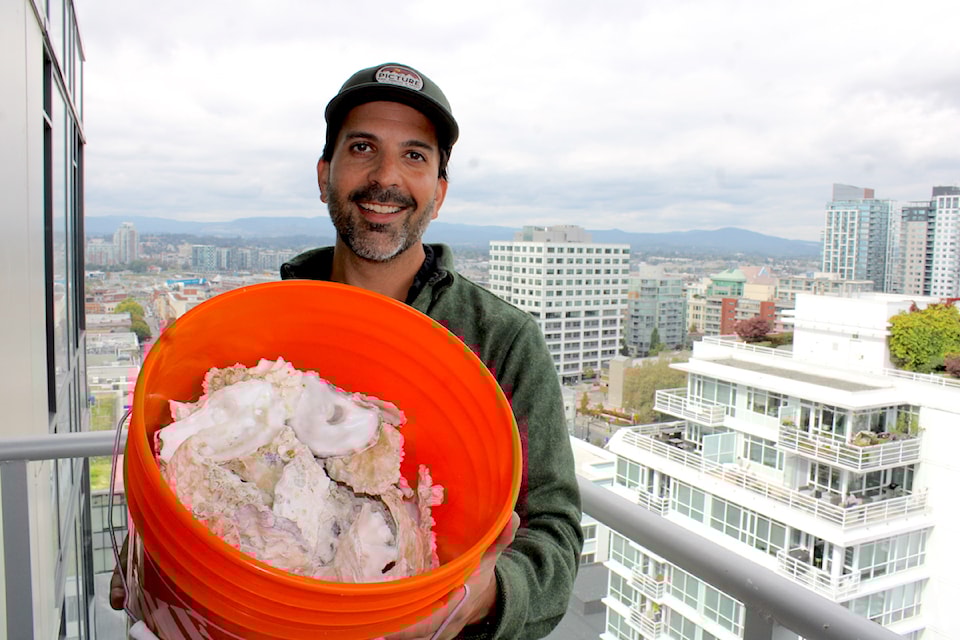 Raj Behari, Shellter founder, poses with oyster shells he stores on the balcony of his Victoria apartment. He hopes to turn the discarded shells into nutrient-rich compost and road de-icer.