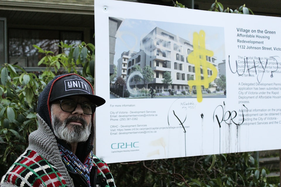 Kym A. Hines stands by the vandalized sign announcing Village on the Greens redevelopment.
