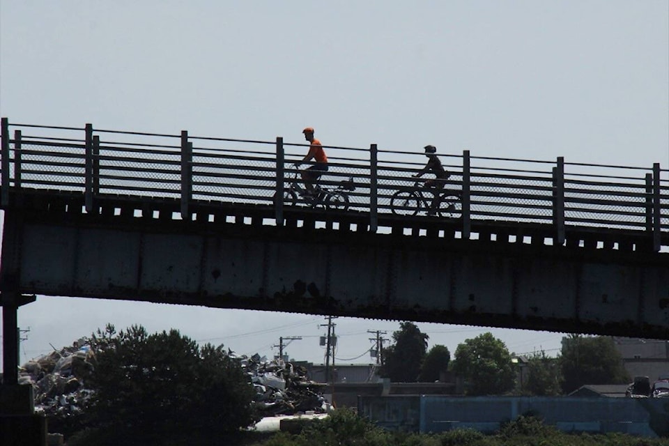 Cyclists traverse the Selkirk Trestle in Victoria on a warm summer afternoon. (Christine van Reeuwyk/News Staff) 