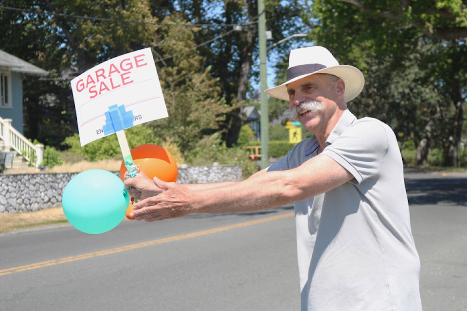 Raulph Schoeddert encourages drivers to stop at his garage sale, held in Oak Bay as part of Garagellenium on Saturday (July 22). (Bailey Moreton/News Staff) 