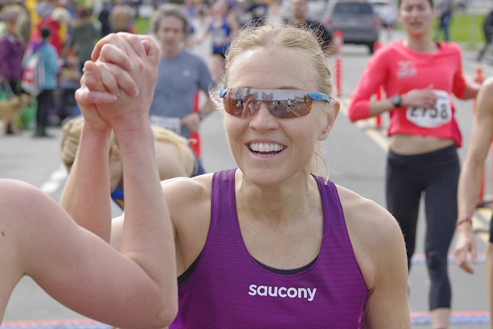 Victoria’s Marilyn Arsenault gets a congratulatory high-five after she crossed the finish line in Sunday’s Bazan Bay 5K race in Sidney. (Steven Heywood/News Staff)