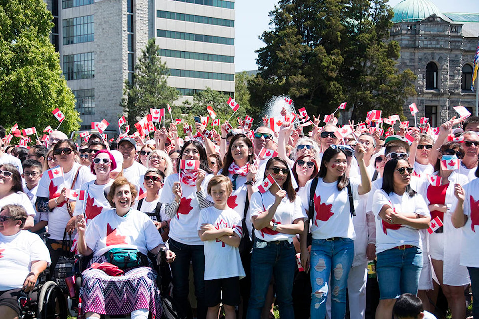 Thousands wave Canadian flags for the camera during the formation of living flag on the lawn of the BC Legislature on Monday. (Nina Grossman/News Staff)