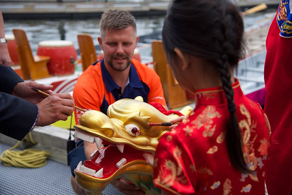 Miyu Loo (right) dotted the eyes of dragon boat head while Bryce Butkiewicz from the Fairway Gorge Paddle Club supports the head. (Nicole Crescenzi/News Staff)