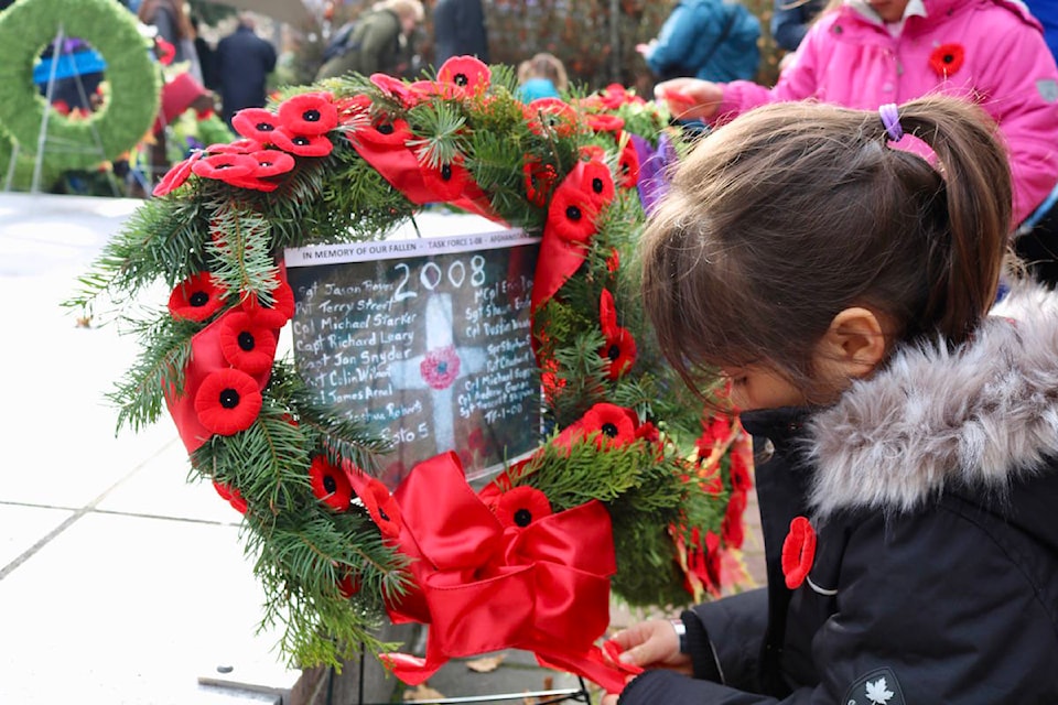 Elizabeth Chow adds extra poppies to the home-made wreath she made with her younger sister, Catherine, at Veterans Memorial Park in Langford. (Aaron Guillen/News Staff)
