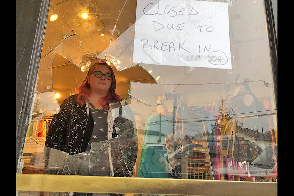 Tina Taylor looks through the broken glass of the front door at her business, Buttons’n’Bows Fabric Store, which was broken into sometime over the Halloween weekend. (Travis Paterson/News Staff)