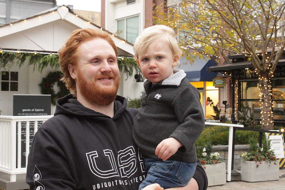 Rob Grant and his one-year-old, William, took in the Christmas decorations at Uptown Shopping Centre on Nov. 14 but plan to get their gifts online. (Devon Bidal/News Staff)