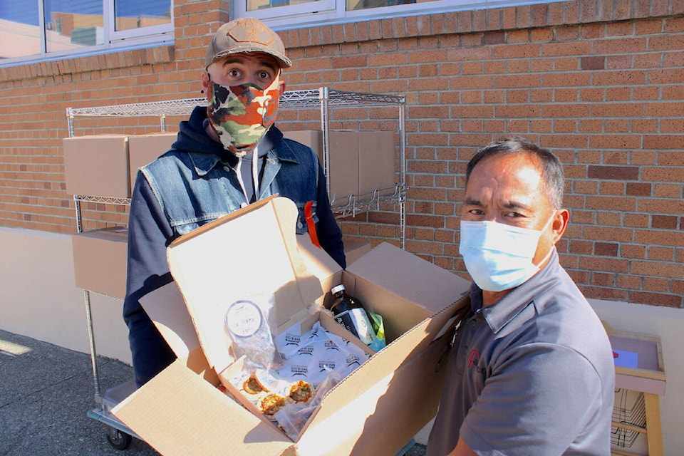 Jones Bar-B-Que and The Ruby owner Chris Jones, left, with Royal Jubilee housekeeper and hospital hero Daniel Dolores as they hold one of the 200 hampers being sent to every Greater Victoria hospital department on Oct. 8. (Jake Romphf/News Staff)