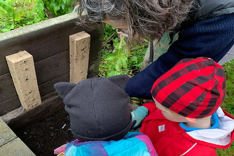 Paula McCormick, youth programs coordinator, helps children in the garden on a rainy day. (Photo courtesy of Erica Van Dyk)