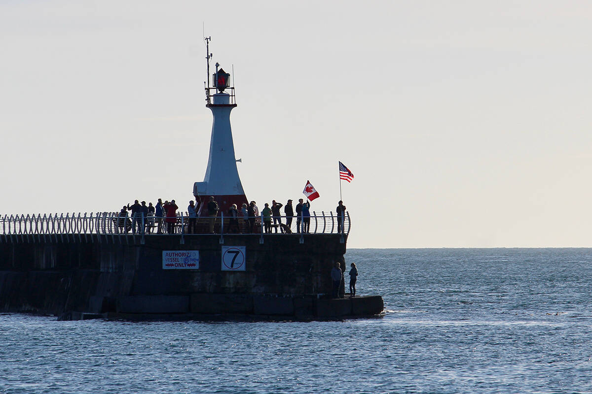 Onlookers at Ogden Point Pier welcome the M.V. Coho with American and Canadian flags. Amy Attas Photo.