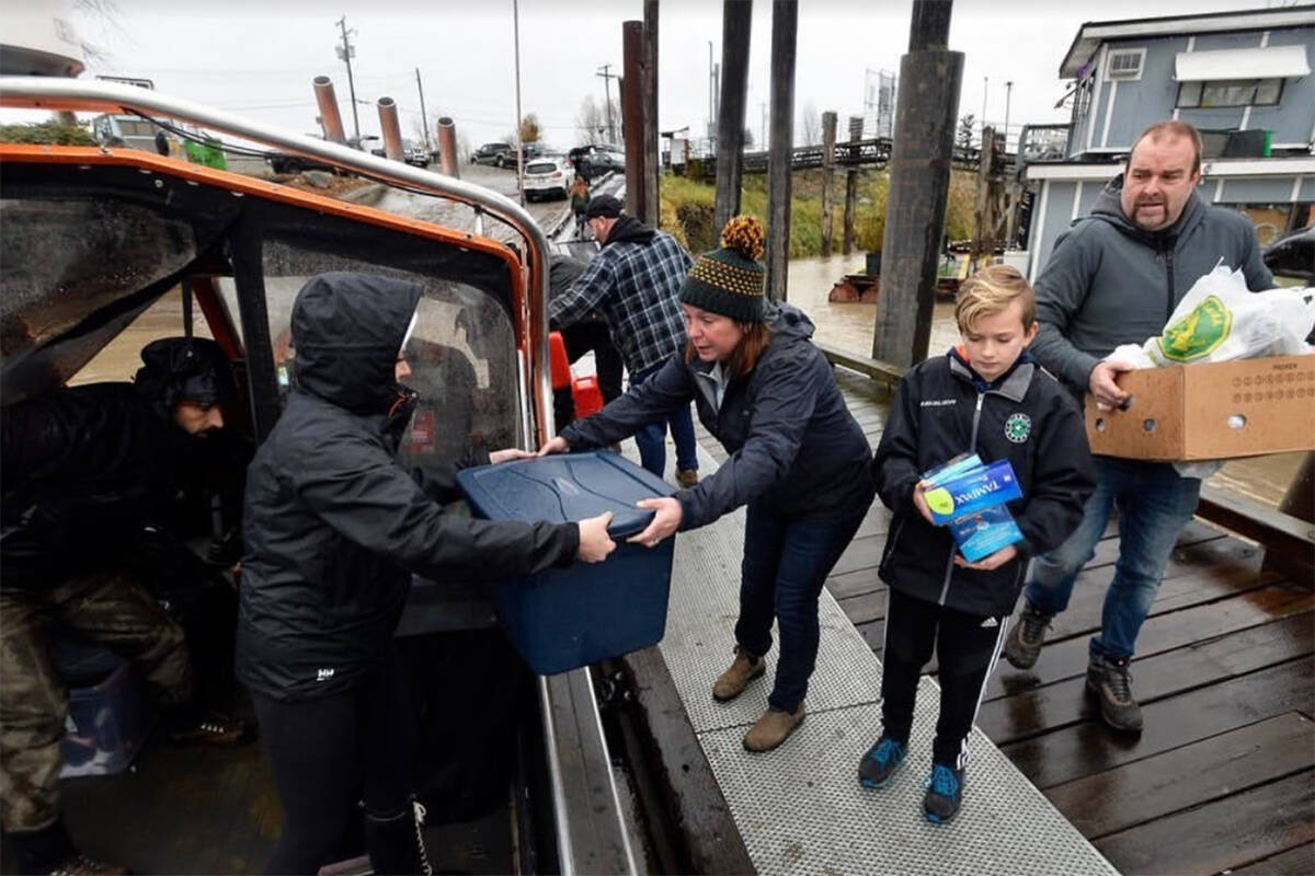 Volunteers from River Wrangler Sportfishing in the Mission Hills community deliver donations by boat after the floods affected dairy farms in Abbotsford in November 2021
