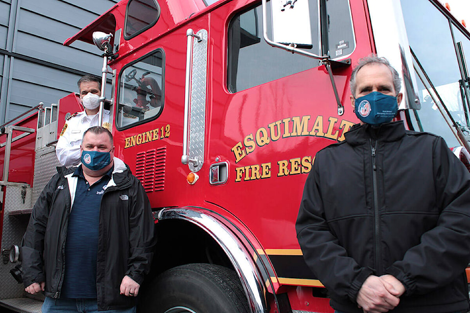 First Nations’ Emergency Services Society members Dean Colthorp, left, and Reo Jerome pose beside the truck donated to the society Feb. 1 by Esquimalt Fire Rescue. Fire Chief Steve Serbic stands on the engine. (Jake Romphf/News Staff)