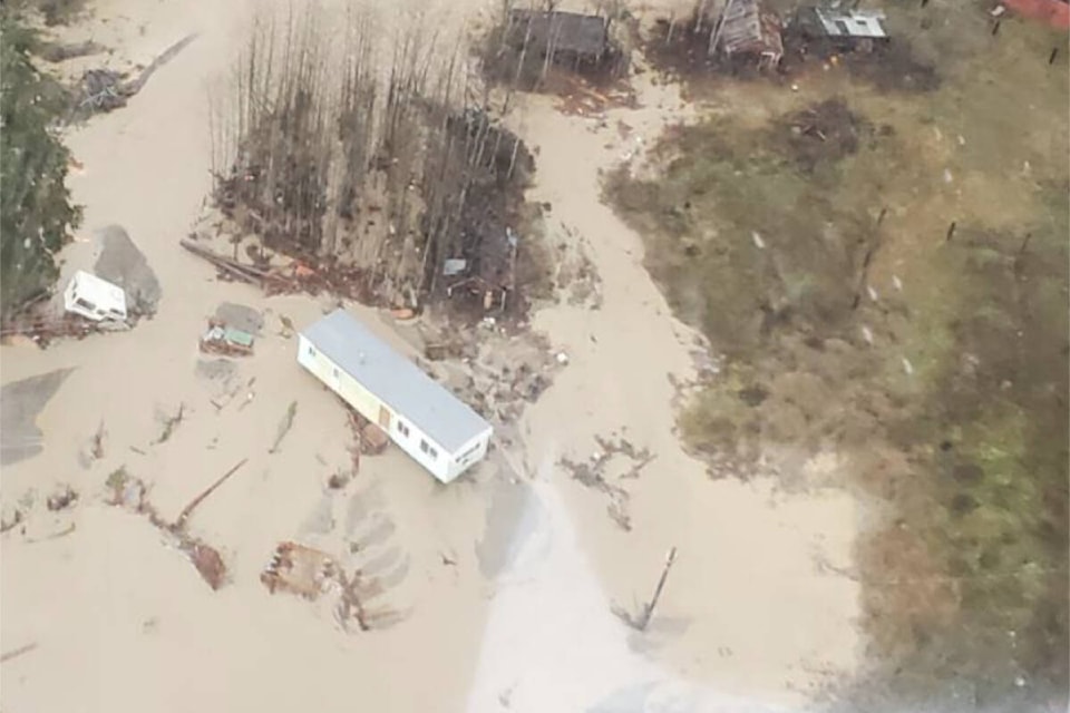 A camper, green bin, mobile home and household debris floating in the Tulameen River. (BC Government photo)