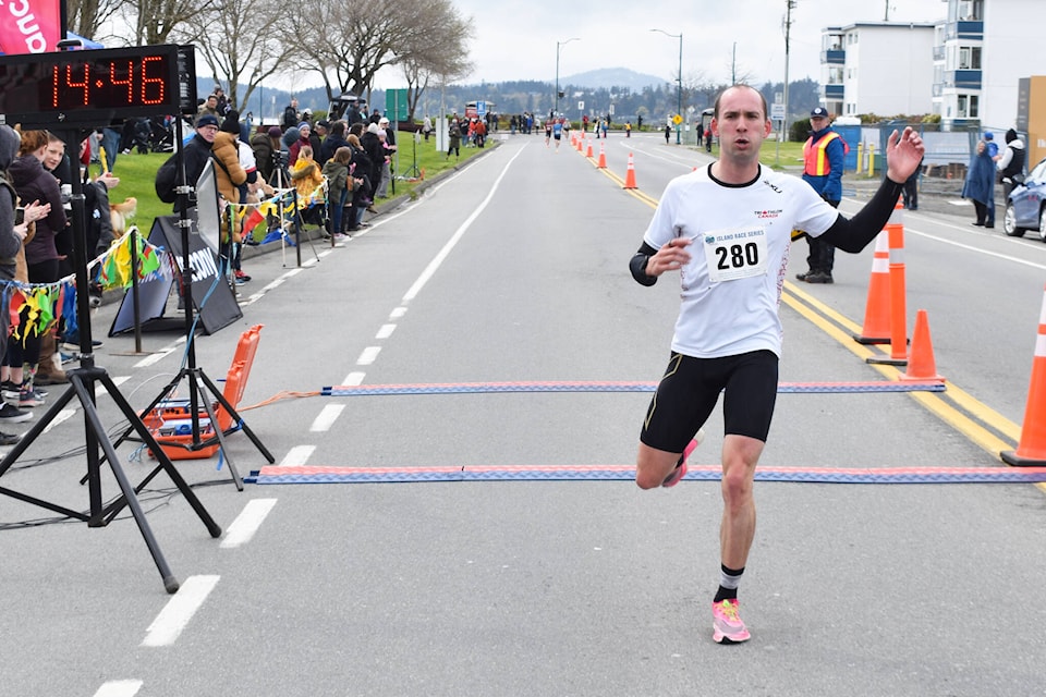 Victoria runner Aiden Longcroft-Harris crosses the finish line on Lochside Drive in Sidney during Sunday’s Bazan Bay 5K. He was first in his category, men age 20 to 24, and second overall among the field of 455 runners. (Wolf Depner/News Staff)