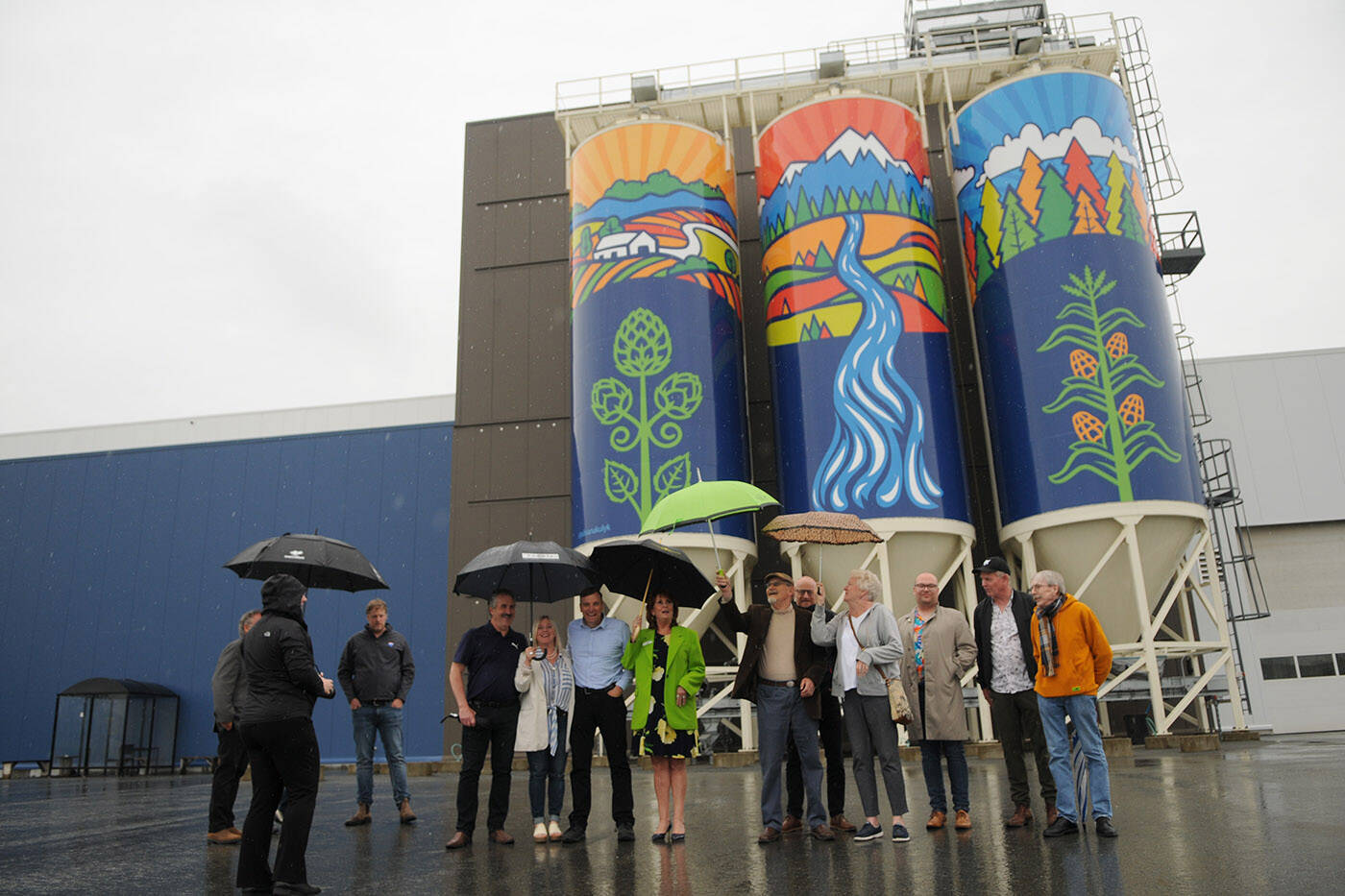 Members of the public art advisory committee line up for a photo in front of Gifts of Nature, a public art piece installed on silos outside the Molson Coors Fraser Valley Brewery and unveiled on Thursday, June 9, 2022. The piece was designed by Chilliwack artist Silvana Kulyk. (Jenna Hauck/ Chilliwack Progress)