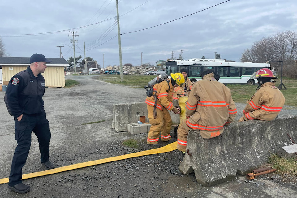 Reed MacPhail instructs a student from Esquimalt High School on how to connect a water hose to a fire hydrant during the youth fire program, March 21. (Hollie Ferguson/News Staff)