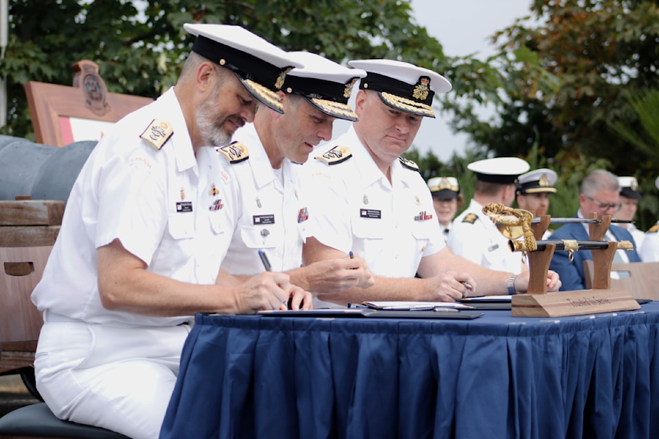 Rear Admiral Christopher Robinson, left, Vice-Admiral Angus Topshee and Rear Admiral David Patchell sign the change of command documents on Tuesday, Aug. 5.
