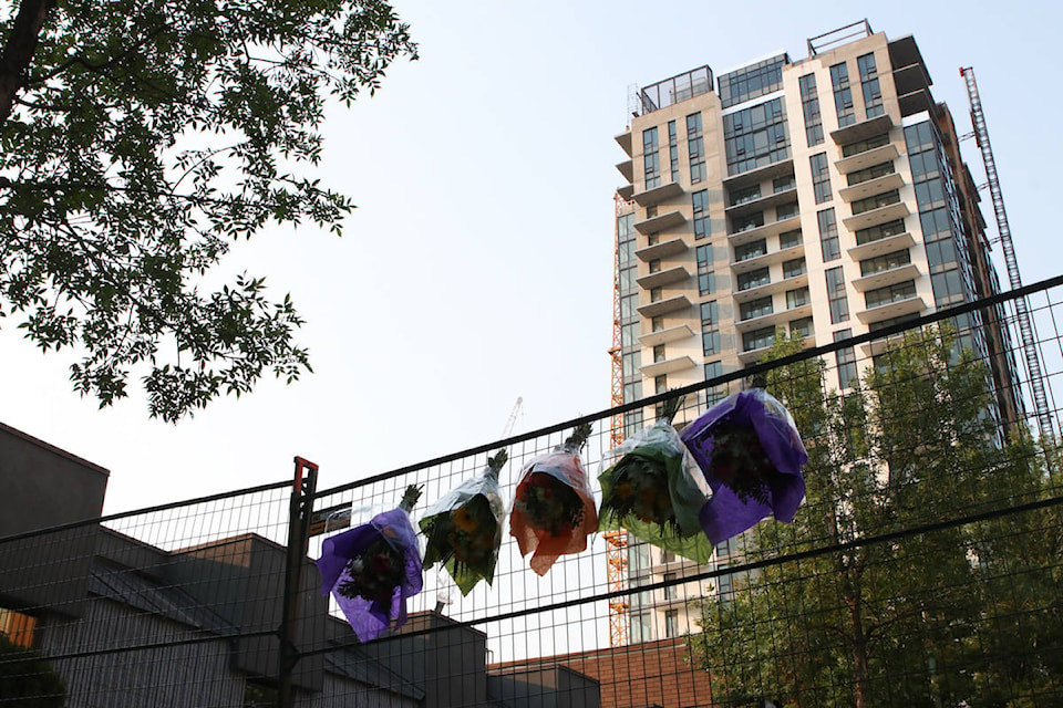 Flower bouquets hang from a gate on St. Paul Street, with the remains of the crane still standing in the background near the site of the collapse. (Aaron Hemens/Capital News)