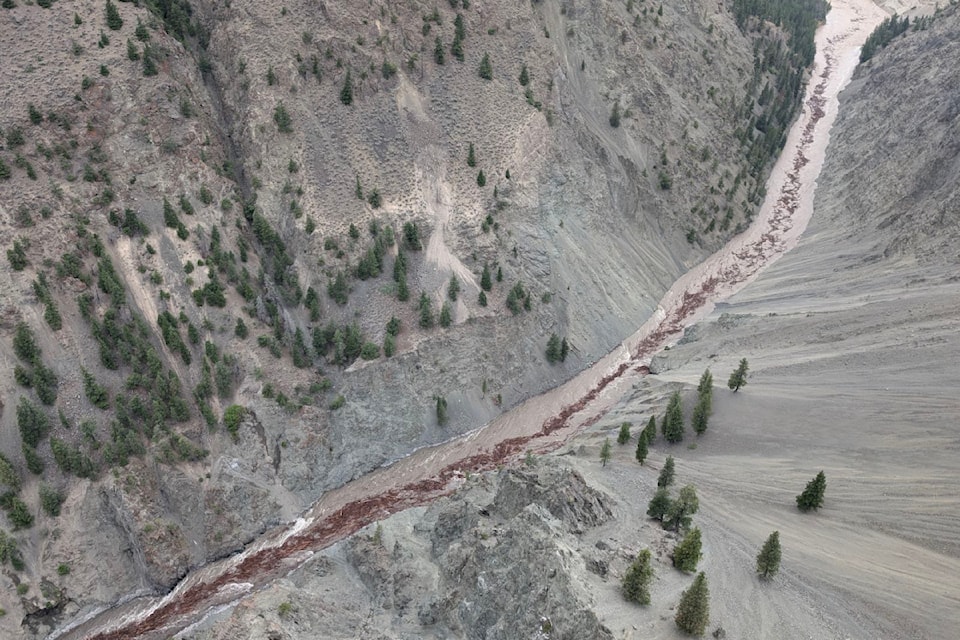 An aerial photo shows debris and logs moving down the Chilcotin River after the landslide blocking it began to give way on Monday morning, Aug. 5, 2024.