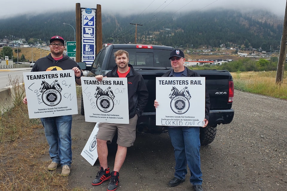 CN workers and Teamsters Canada union members Gage Ringer, conductor, left, Grant Norquay, conductor, and Jeff Iggulden, locomotive engineer stand with signs Thursday, Aug. 22 in Williams Lake. 