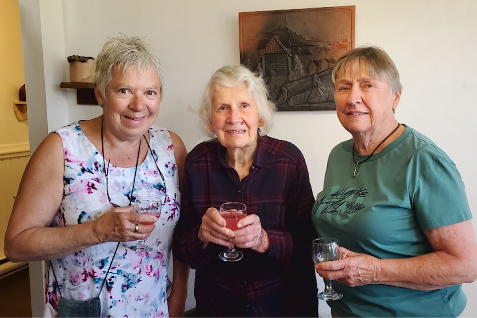 Cariboo Potters' Guild members Lesley Lloyd, left, and Buff Carnes, right, salute the guild's founder Anna Roberts during the opening reception of an exhibit of Roberts' works at the Station House Gallery, Friday, July 12, 2024. 