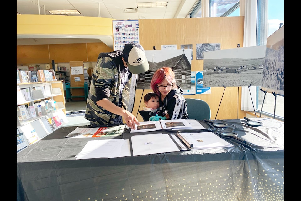 Theresa Inscho (right) with her partner Wilmer Elkins-Billy (left) and daughter, Katori Inscho-Elkins, looking through photos of students who attended St. Joseph Mission residential school. 