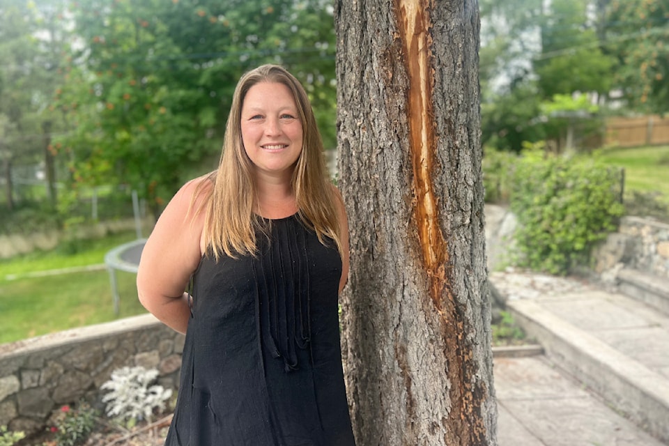 Sara Greig stands next to the Douglas fir tree which was struck by lightning, while she was nearby on Aug. 2.