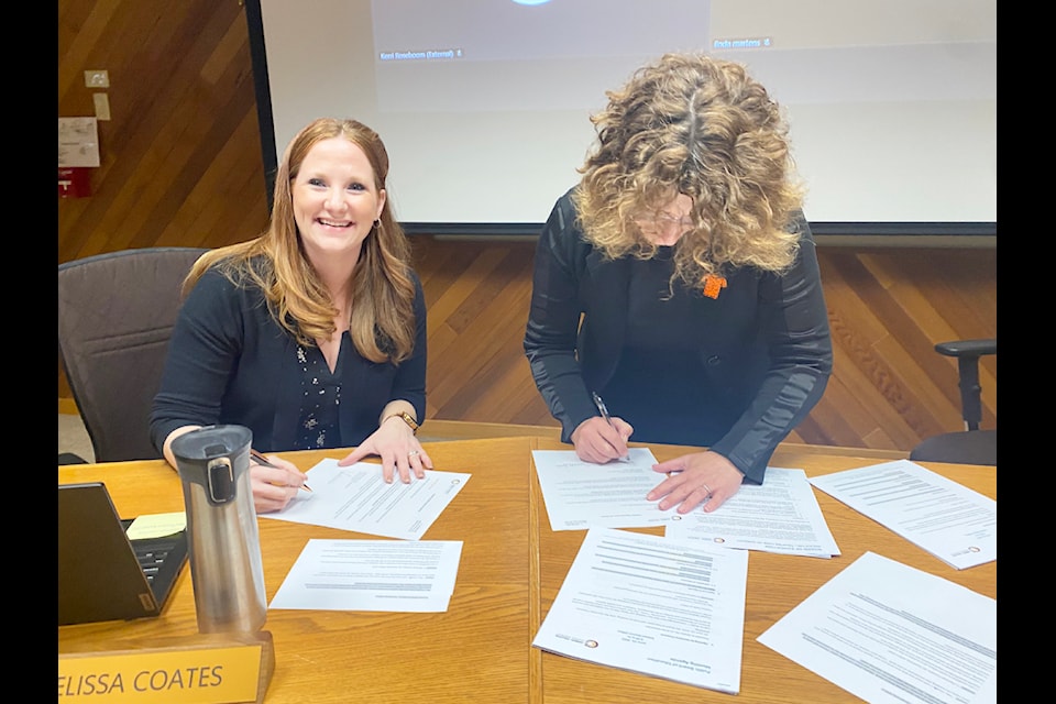 Trustee Coates and Superintendent Lenardon sign papers, finalizing Coates' addition to the board of education. 