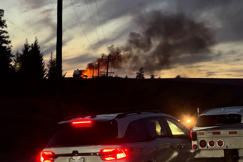 Vehicles line up on Highway 97 as a transport truck burns, halting traffic.