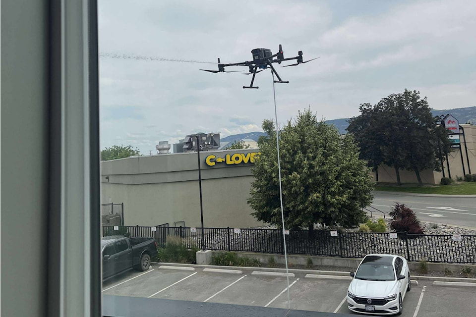 A drone sprays water at the exterior of a building on Kamloops' North Shore on June 17.