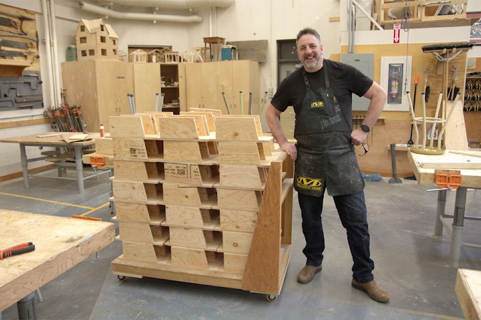 Teacher Andrew Hutchinson stands next to a stack of birdhouses built by his students to support the mountain bluebird program.
