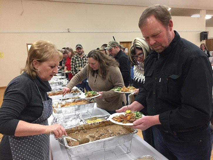 Sandy Callander serves up elk stroganoff to Vivian and Dan Simmons in front.