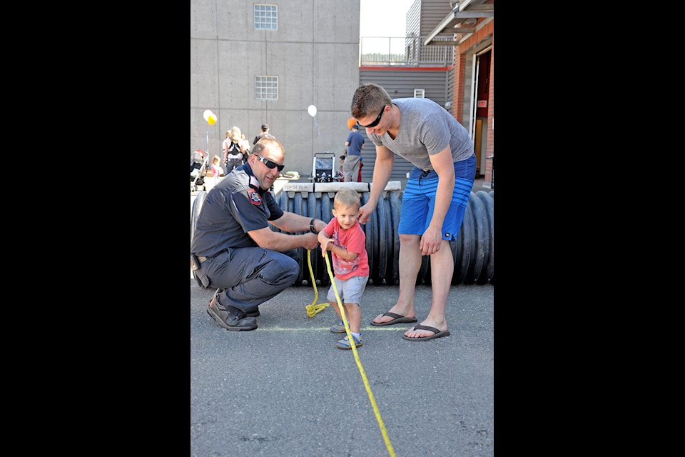 Justin Foote and son, Luke Foote, 2, pull in a rope in the firefighters challenge for children at the Williams Lake Fire Department’s annual open house.