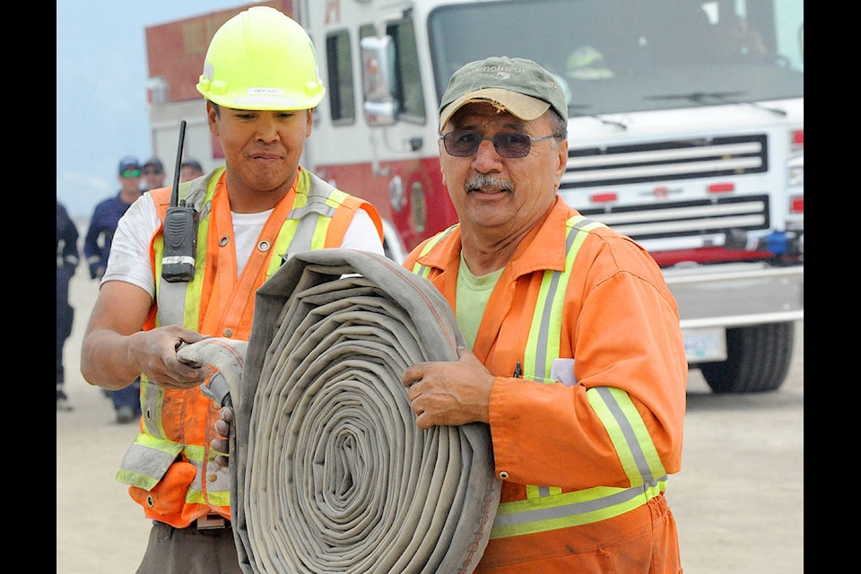 Wanye McKay and Emery Alec of Cantex Okanagan roll up some water hoses after fighting fire Monday. (Angie Mindus photo)