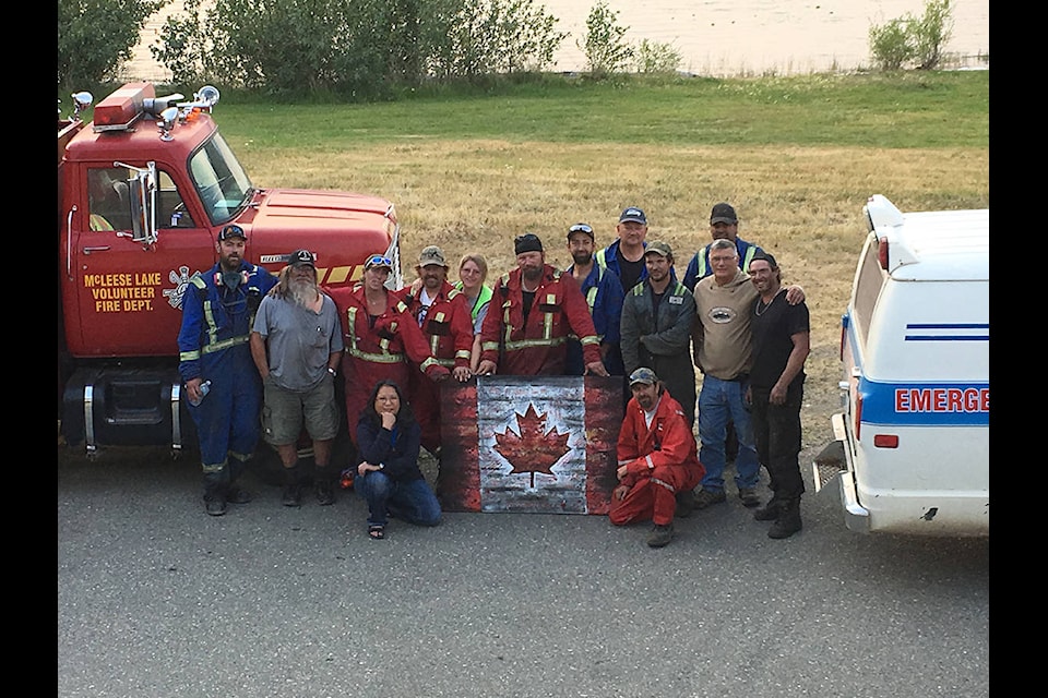 Members of the McLeese Lake Volunteer Fire Department accepted the gift of a Canadian flag with messages of hope from Fort Mac crews that the local department will one day have its own fire hall.