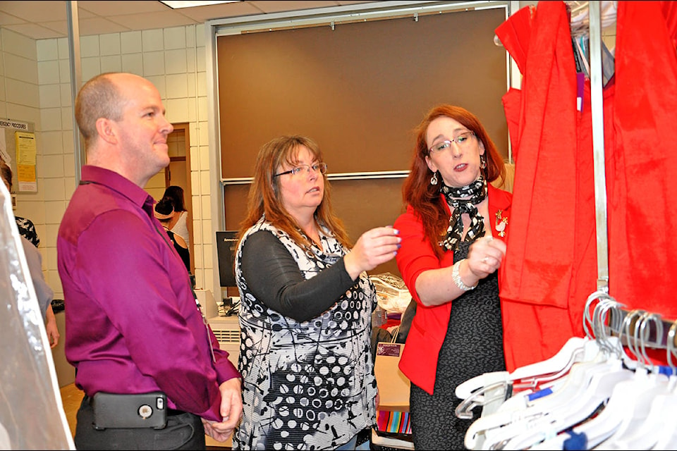 Brides & Belles owner Kimberly Futcher (middle) shows Bill Price and Lisa Price some dresses Sunday at the bridal and grad extravaganza in the TRU gymnasium. (Greg Sabatino photos)